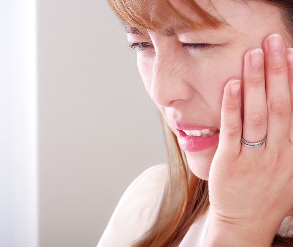 歯の痛みで頬を押さえる女性