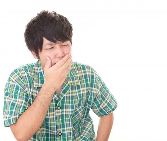 奥歯の痛みで口元を押さえる男性